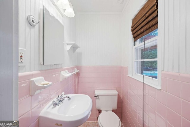 bathroom with ornamental molding, tile walls, sink, and toilet