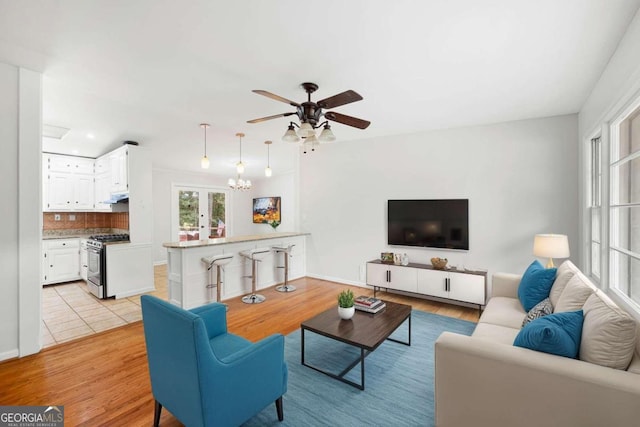 living room featuring light wood-type flooring, ceiling fan, and french doors