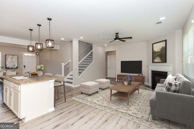 living room with ceiling fan, light wood-type flooring, and sink