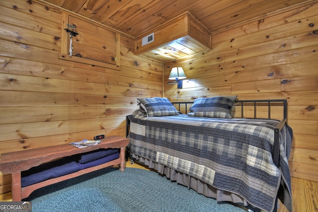 carpeted bedroom with wood ceiling and wooden walls