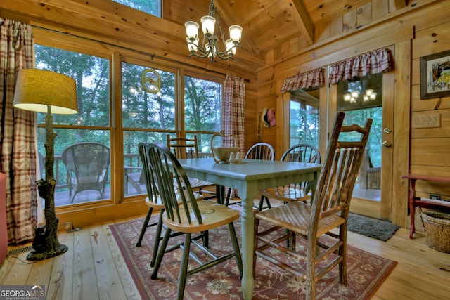 dining area featuring wood ceiling, lofted ceiling with beams, light wood-type flooring, an inviting chandelier, and wooden walls