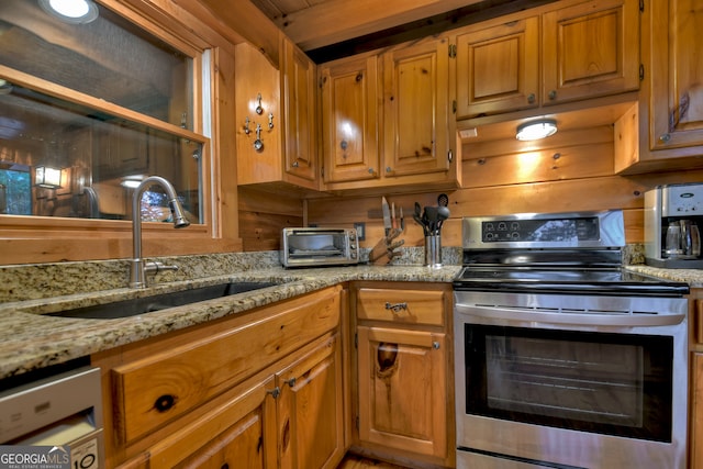 kitchen featuring light stone countertops, appliances with stainless steel finishes, and sink