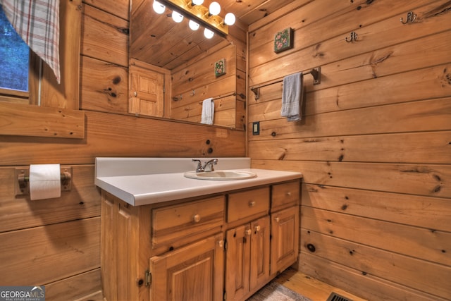 bathroom with wooden ceiling, wood walls, and vanity