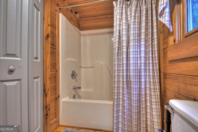 bathroom featuring wood walls, toilet, and shower / bath combination with curtain