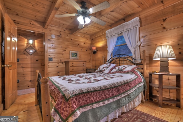 bedroom featuring ceiling fan, wooden walls, light hardwood / wood-style floors, and beam ceiling