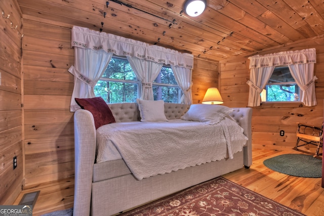 bedroom with wooden walls, vaulted ceiling, wooden ceiling, and hardwood / wood-style floors