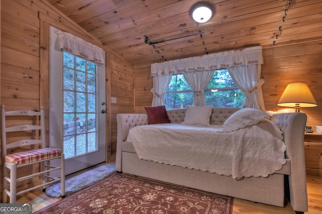 bedroom featuring wooden walls, hardwood / wood-style floors, vaulted ceiling, and wooden ceiling