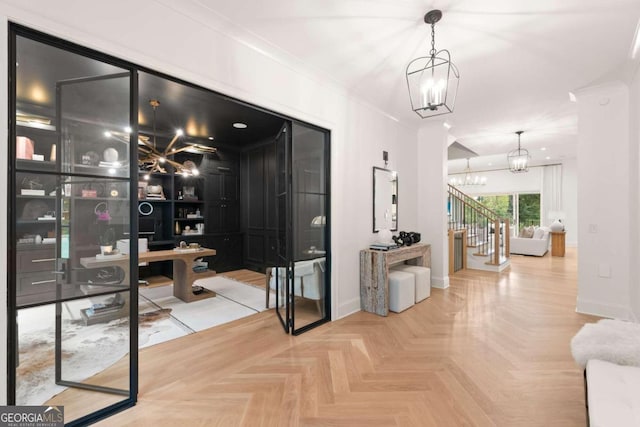 foyer entrance with ornamental molding, a chandelier, and parquet flooring