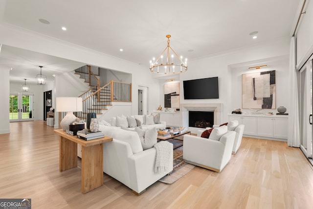 living room featuring an inviting chandelier, light hardwood / wood-style flooring, and ornamental molding