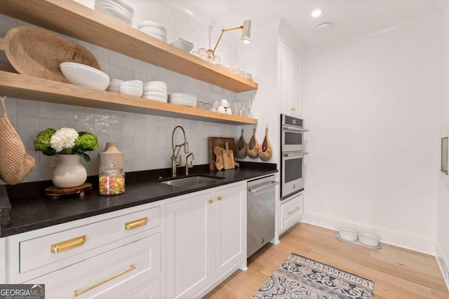 bar featuring light hardwood / wood-style floors, sink, white cabinetry, stainless steel appliances, and backsplash