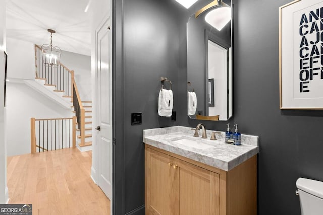 bathroom featuring hardwood / wood-style floors, a chandelier, vanity, and toilet