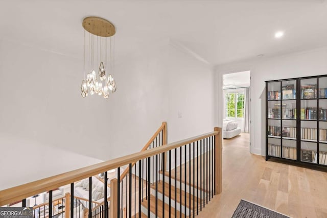 corridor with light hardwood / wood-style floors and a notable chandelier