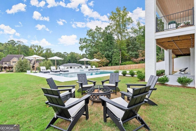 view of yard with a balcony, an outdoor fire pit, a fenced in pool, and a patio area