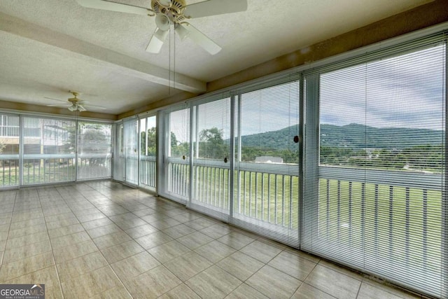 unfurnished sunroom featuring ceiling fan and a wealth of natural light