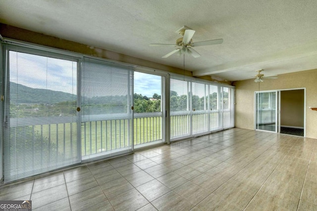 unfurnished sunroom with beam ceiling and ceiling fan