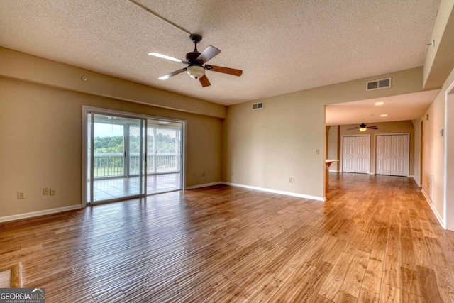 empty room with light wood-type flooring, ceiling fan, and a textured ceiling