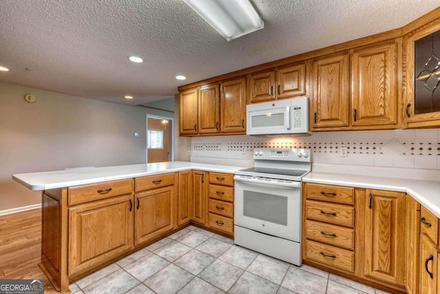 kitchen featuring light tile patterned flooring, kitchen peninsula, white appliances, a textured ceiling, and backsplash