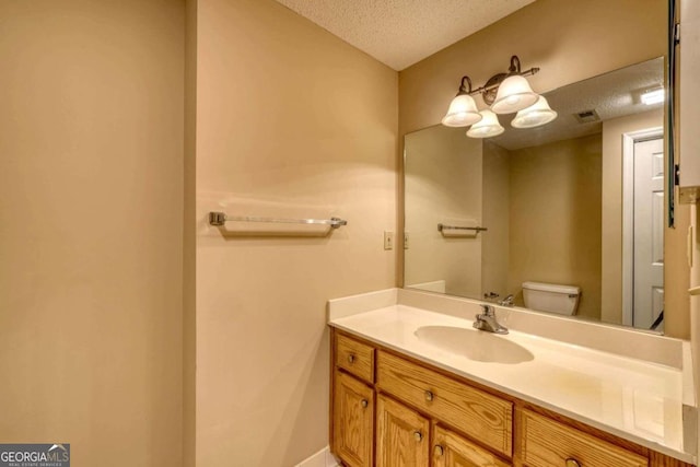 bathroom featuring vanity, a textured ceiling, and toilet