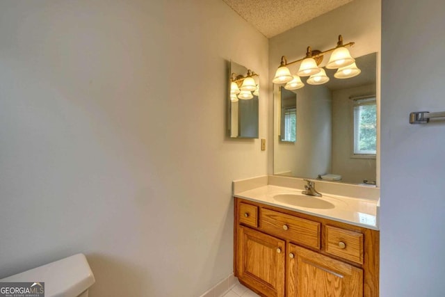 bathroom with vanity, toilet, a textured ceiling, and tile patterned floors