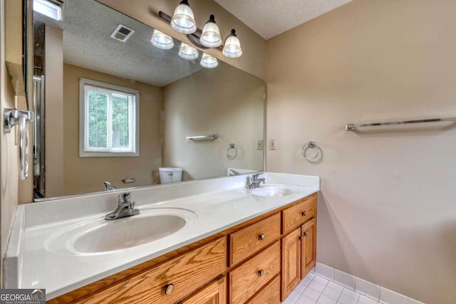 bathroom featuring a textured ceiling, vanity, toilet, and tile patterned floors