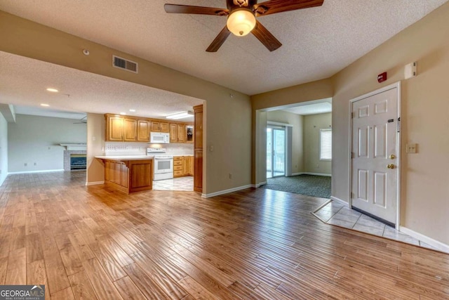 unfurnished living room with light wood-type flooring, a textured ceiling, and ceiling fan