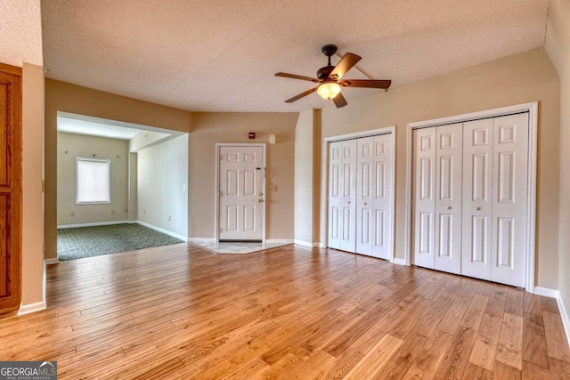 interior space featuring a textured ceiling, two closets, and light hardwood / wood-style flooring