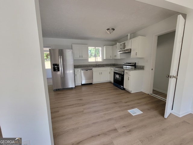 kitchen with white cabinets, sink, a textured ceiling, stainless steel appliances, and light wood-type flooring