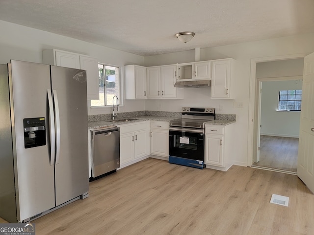 kitchen with sink, white cabinets, light hardwood / wood-style flooring, stainless steel appliances, and light stone countertops