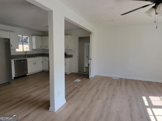 kitchen featuring appliances with stainless steel finishes, white cabinetry, light wood-type flooring, ceiling fan, and sink