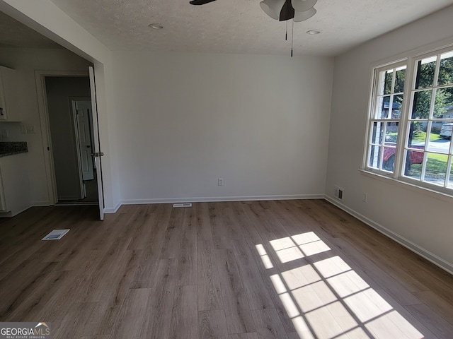 spare room featuring a textured ceiling, ceiling fan, and light hardwood / wood-style flooring