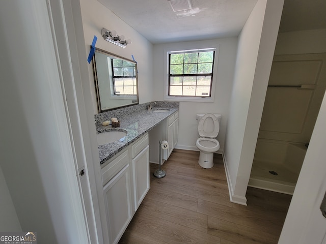 bathroom featuring vanity, a shower, hardwood / wood-style floors, and toilet