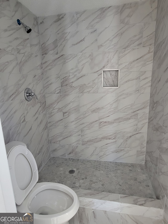 bathroom with toilet and tiled shower