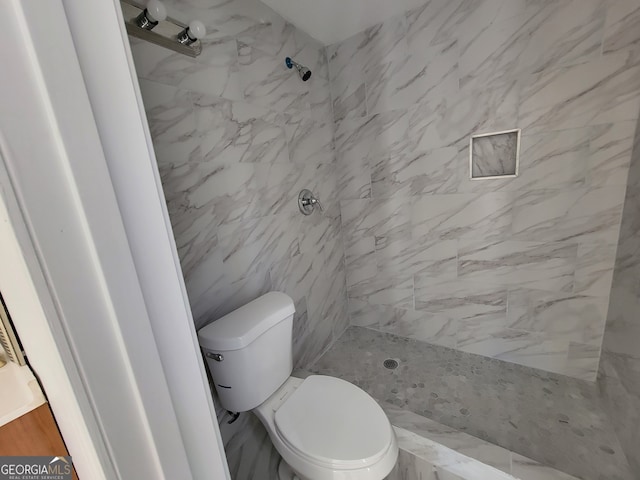 bathroom featuring a tile shower and toilet