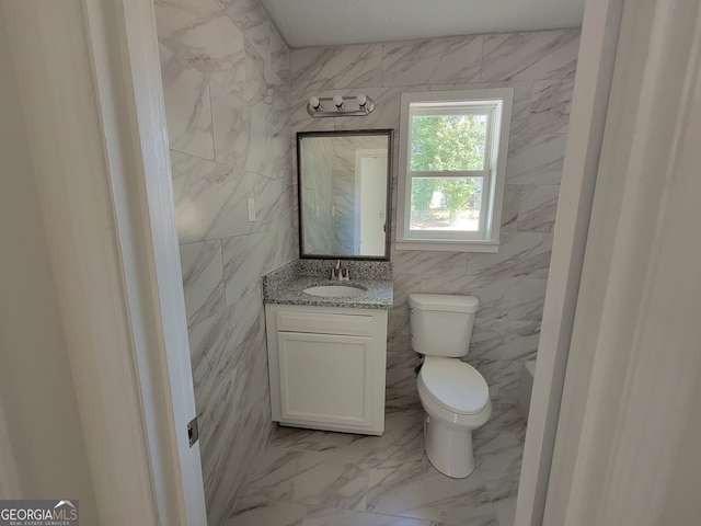 bathroom with tile walls, vanity, and toilet