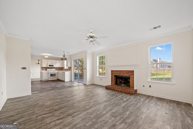 unfurnished living room featuring a brick fireplace, dark hardwood / wood-style flooring, ceiling fan, and crown molding