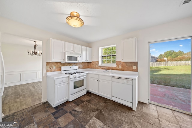 kitchen featuring white cabinets, hanging light fixtures, and white appliances