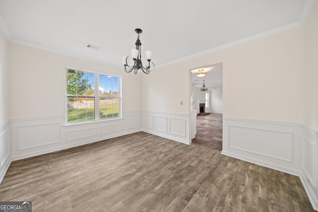 unfurnished dining area with a notable chandelier, hardwood / wood-style flooring, and crown molding