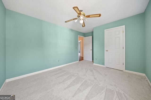 unfurnished bedroom featuring ceiling fan, a textured ceiling, and light colored carpet