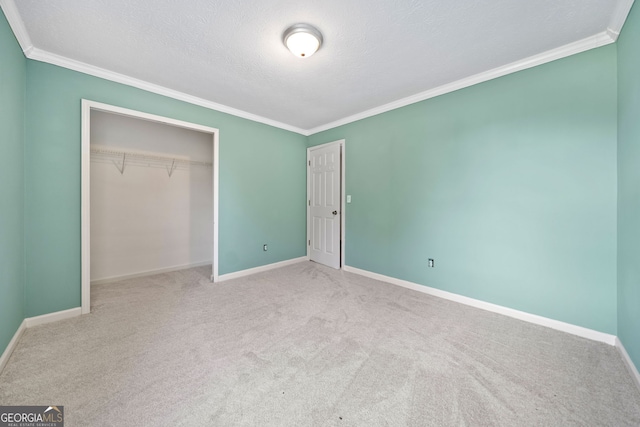 unfurnished bedroom featuring a closet, a textured ceiling, light colored carpet, and ornamental molding