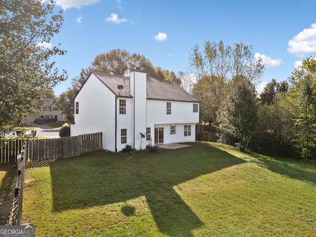 rear view of house with a patio and a lawn