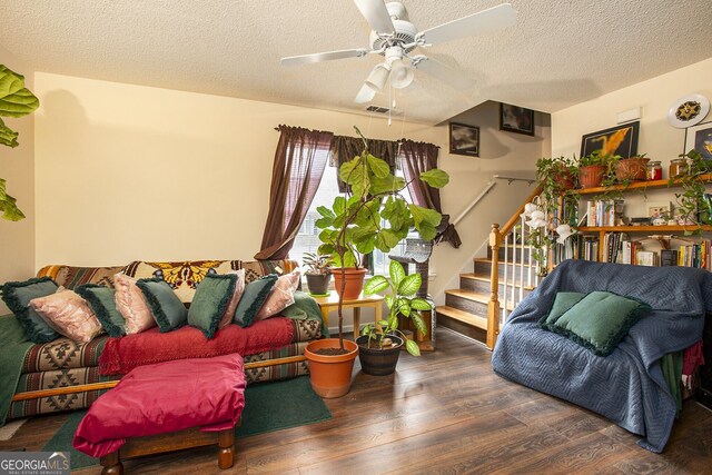 living room with a textured ceiling, ceiling fan, and dark wood-type flooring