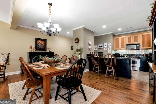 dining space featuring an inviting chandelier, light wood-type flooring, ornamental molding, and a textured ceiling