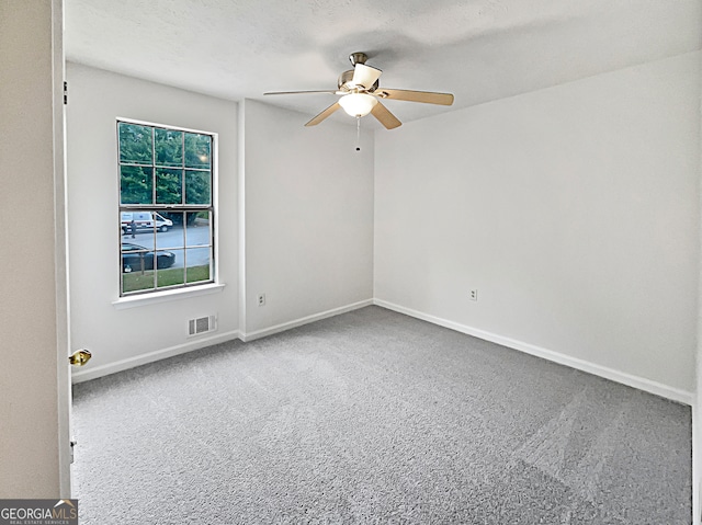 carpeted spare room featuring ceiling fan and a textured ceiling