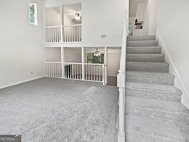 staircase with a healthy amount of sunlight, carpet, and ceiling fan