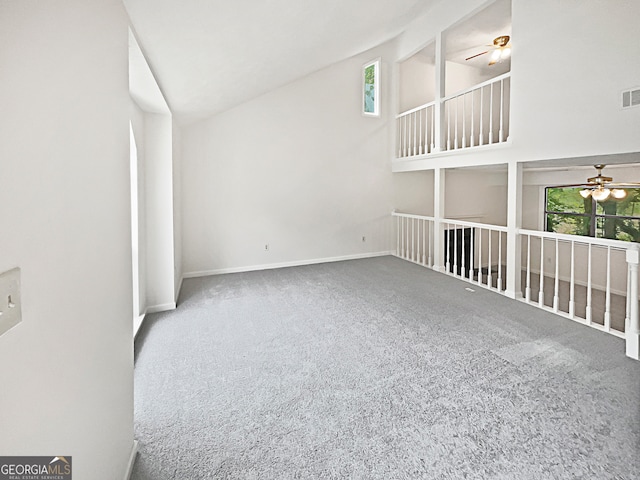 carpeted spare room with ceiling fan and high vaulted ceiling