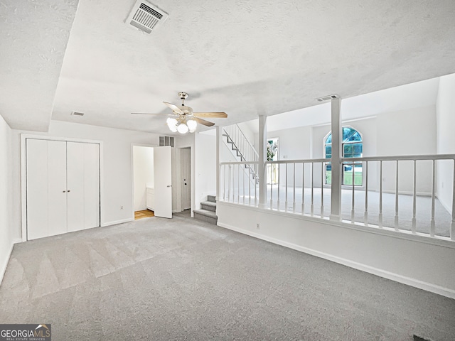 carpeted empty room featuring ceiling fan and a textured ceiling