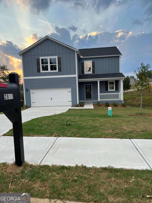 view of front of property featuring a lawn, a garage, and covered porch