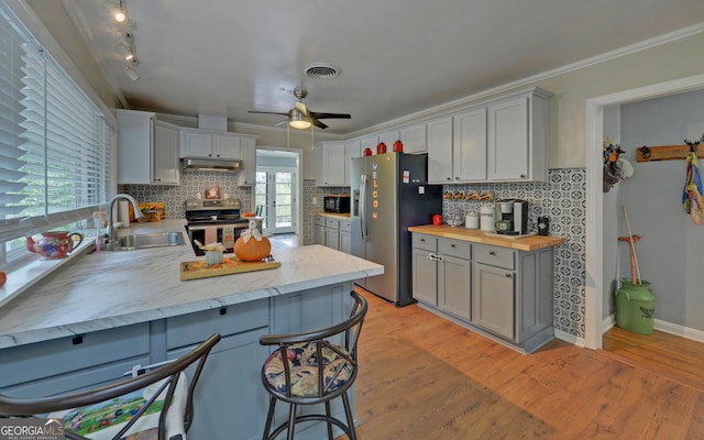 kitchen featuring ceiling fan, ornamental molding, sink, backsplash, and stainless steel appliances