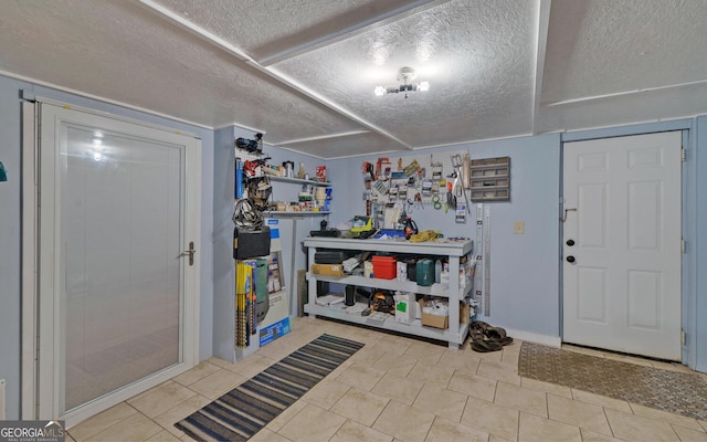 foyer featuring a workshop area, a textured ceiling, and light tile patterned floors