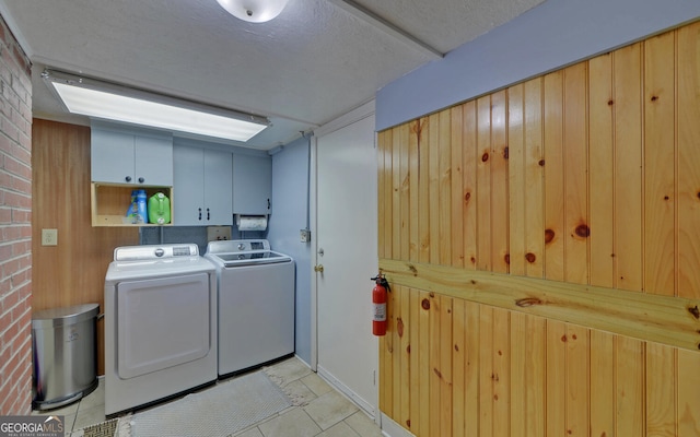 laundry area with washer and clothes dryer, cabinets, and brick wall